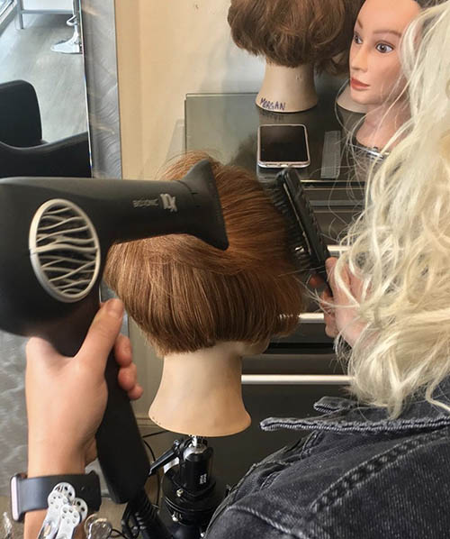 image of future stylist Riley blow drying hair during her apprenticeship
