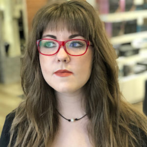 Woman with red glasses and bangs looking away from the camera