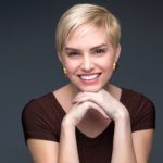 Woman with short blonde pixie cutt smiling and looking at camera