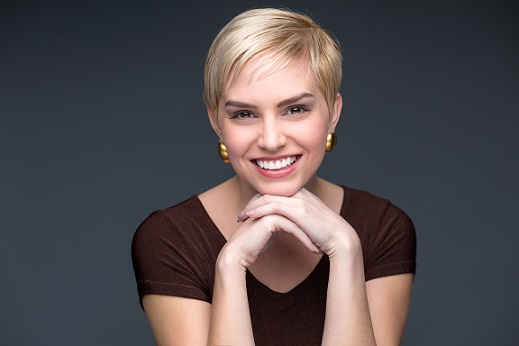Woman with short blonde pixie cutt smiling and looking at camera