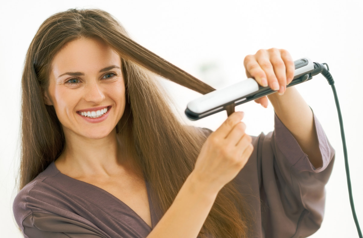 Brunette woman straightening hair