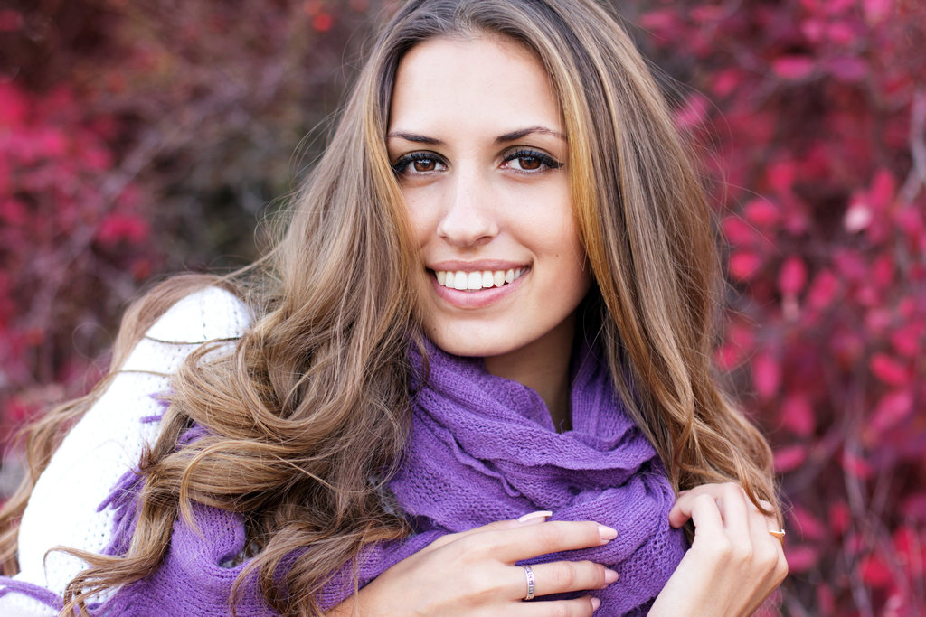 Woman with curly hair and scarf in front of flowers for blog on tips for fine hair