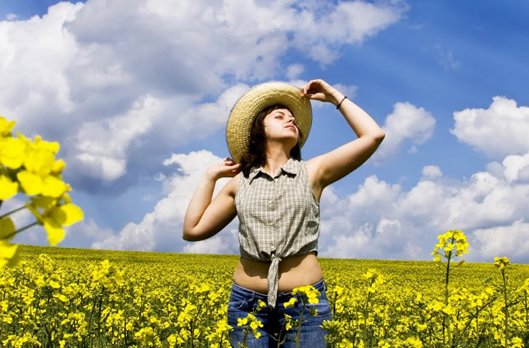 Woman posing with a tan hat in a field of springtime flowers